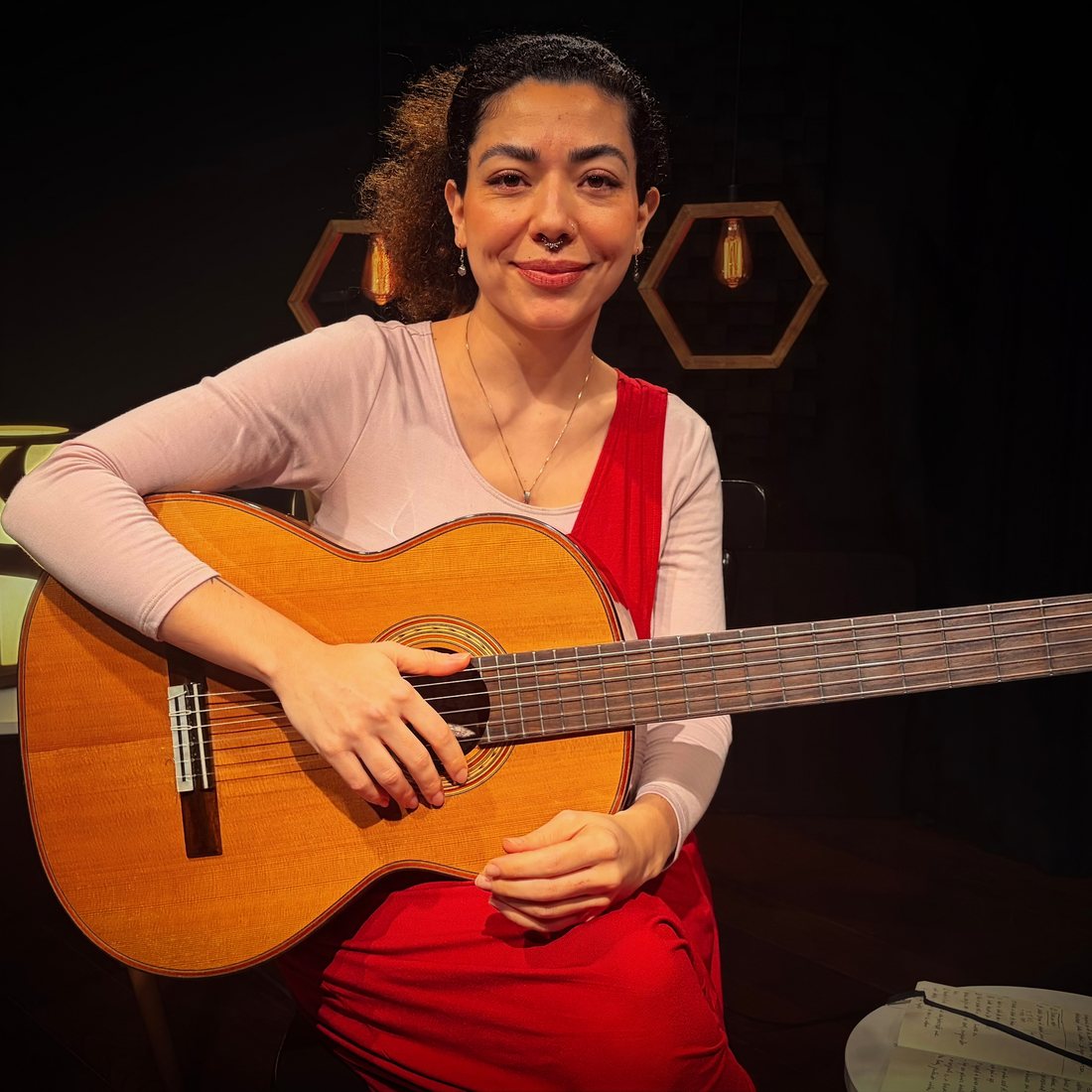Vanessa Moreno sorrindo, com o violão no colo